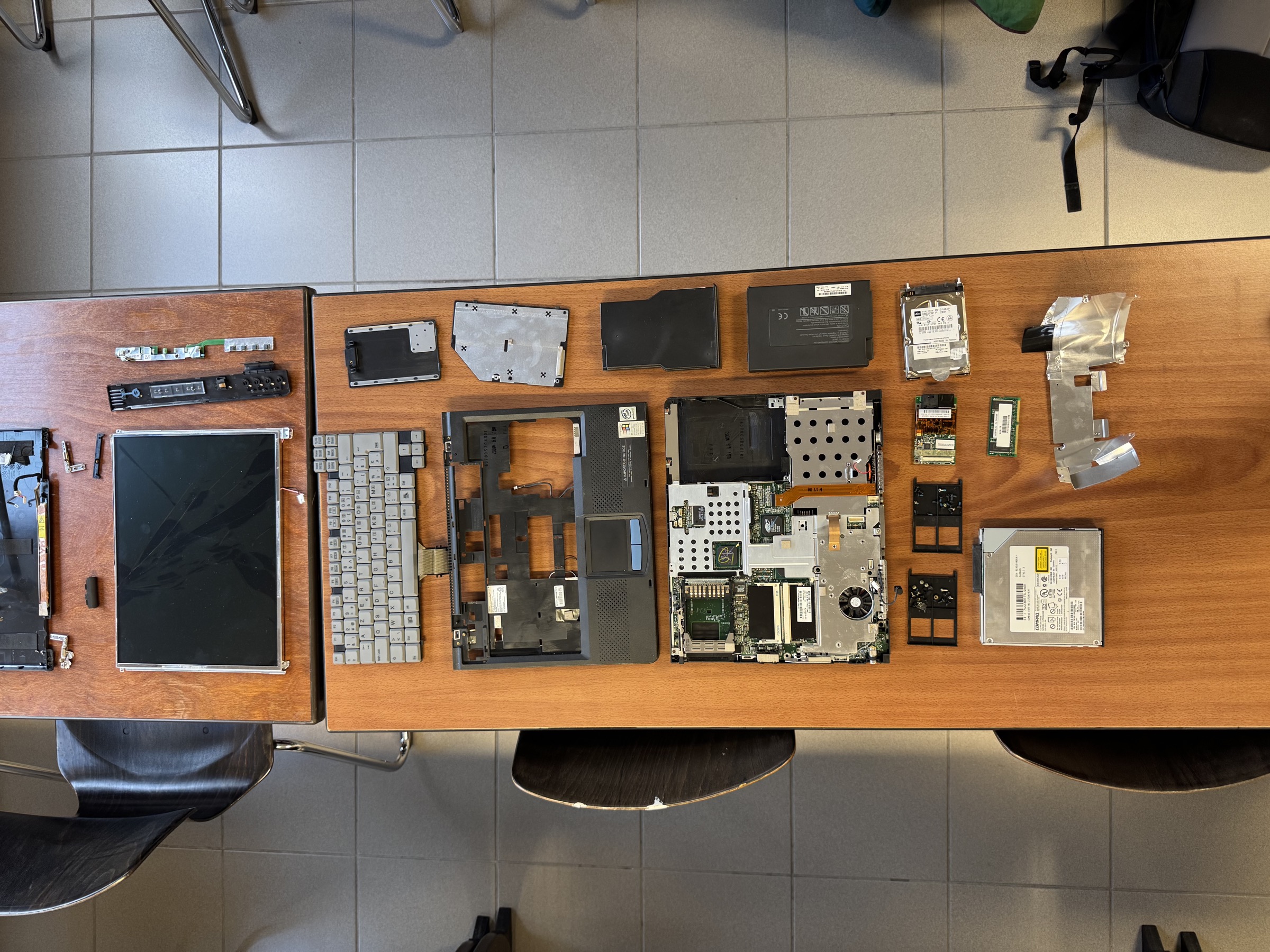 E-waste workshop — a disassembled laptop with all components laid out on a table
